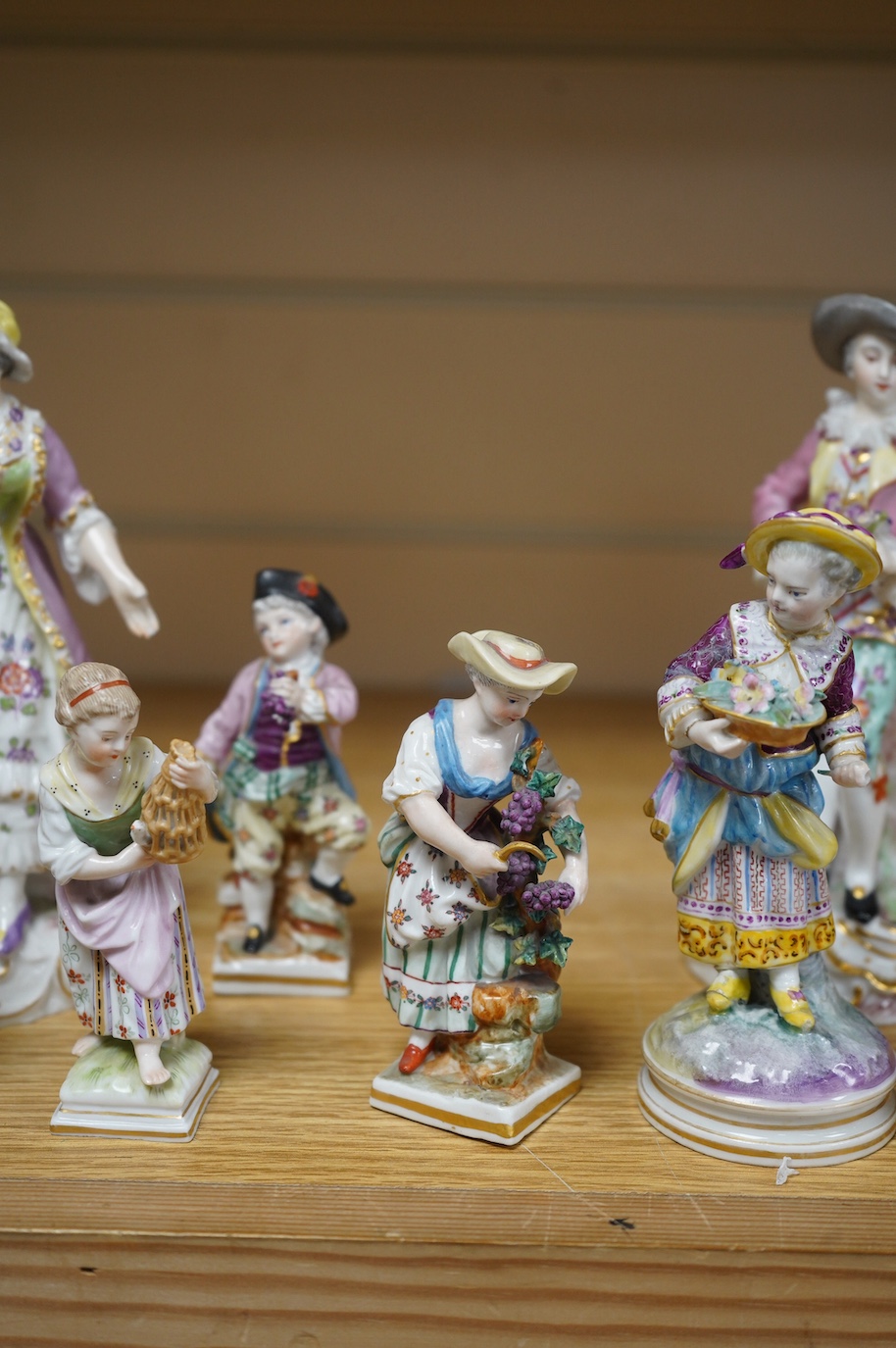 Eight various German porcelain figures, some with crossed sword marks to the bases and a floral encrusted pot and cover, largest 19cm high. Condition - fair, some losses